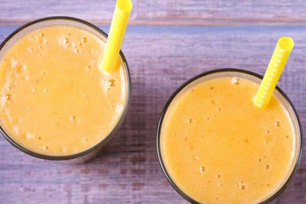 Easy Peach Smoothie Without Yogurt - top down images of 2 peach smoothies recipe on a table
