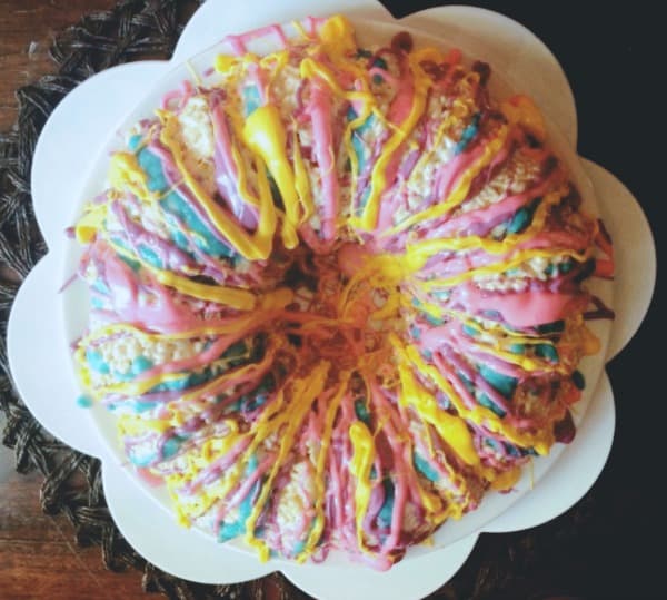 rice krispie cake with pink, blue, and yellow chocolates melted over it