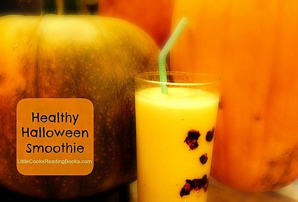 Halloween Drinks: Healthy Halloween Smoothie Recipe orange smoothie with a pumpkin face on the glass sitting in front of pumpkins