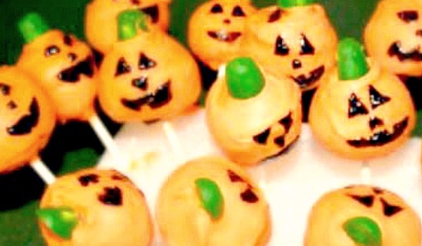 Pumpkin Cake Pops for Halloween pumpkin cake pops with faces sticking into a stand