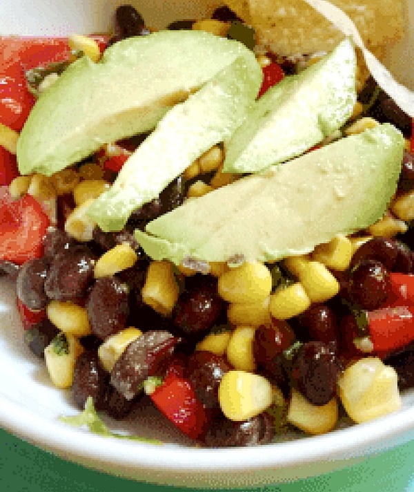 Black Bean and Corn Salad with Avocado slices on top in a white bowl