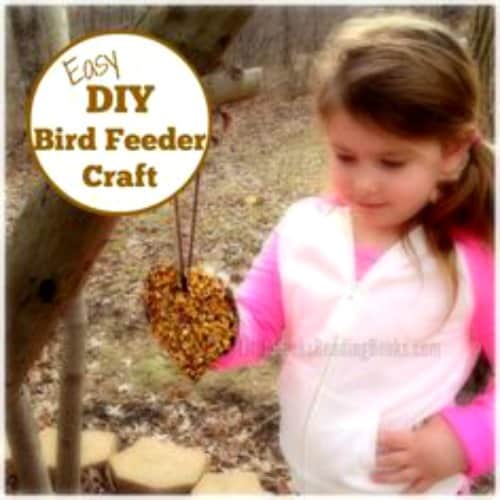 Easy DIY Homemade Bird Feeder Recipe Craft for Kids (homemade bird seed feeder recipe for kids crafts) young girl smiling at hanging bird feeder in tree