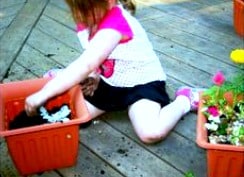 How to Make a DIY Container Fairy Garden for Kids of All Ages girl sitting on deck making a fairy garden in a container