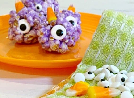 Easy Recipe for Popcorn Balls with Marshmallow For Halloween Treats purple people eater popcorn balls recipe on an orange plate