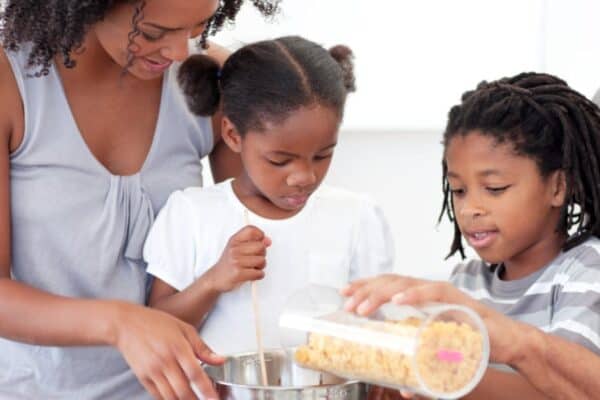 cooking supplies for kid chefs with family pouring ingredients into baking bowl