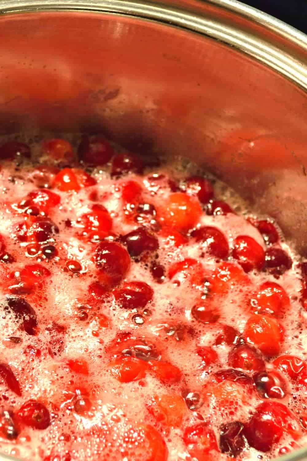 How to make candied cranberries: candied cranberry recipe simmering in small saucepan (crystalized cranberries)