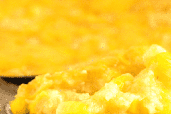 How To Make Corn Casserole In Slow Cooker or Oven close up of corn pudding on spoon