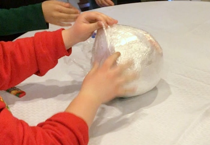 Saran Wrap Ball Game with hands unwrapping cellophane ball