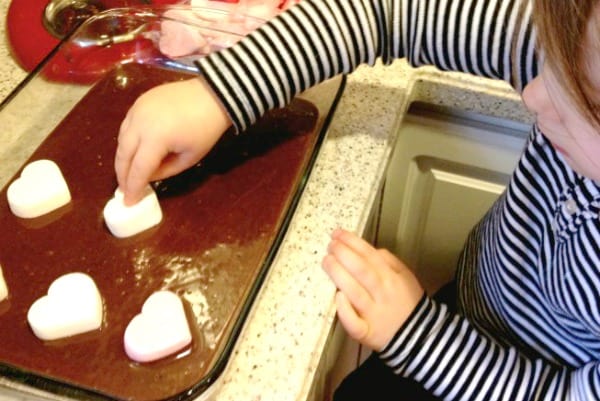 little girl placing heart shaped marshmallows into brownie batter
