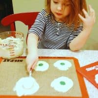 child spreading white chocolate onto a mat