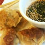 Chinese Dumplings (potstickers) on a plate with chopsticks and potsticker sauce