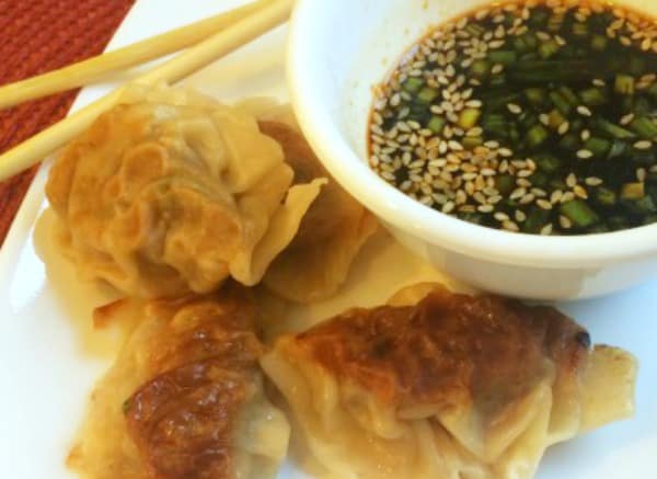 Chinese Dumplings (potstickers) on a plate with chopsticks and potsticker sauce