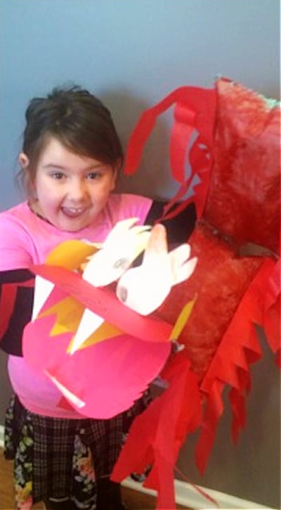 easy Chinese dragon craft for kids young girl laughing and holding a large DIY dragon puppet craft