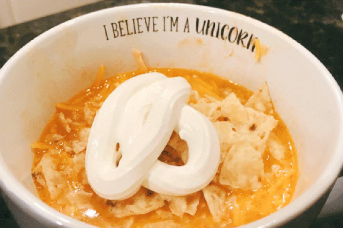 Easy White Bean Chicken Chili In Crock pot chicken chili with sour cream and tortilla chips in bowl