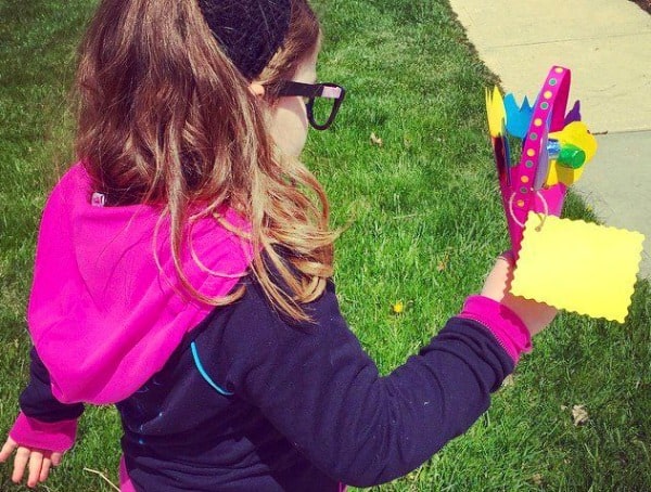 May Day Basket Ideas girl walking outside and carrying a May Day basket made out of pink construction paper