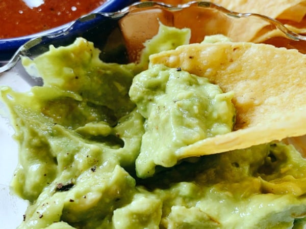 Homemade Guacamole a tortilla chip dipped into a bowl of guacamole