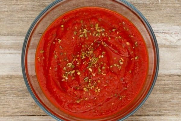 How To Make Pizza Sauce looking down on a bowl of red pizza sauce sitting on a counter