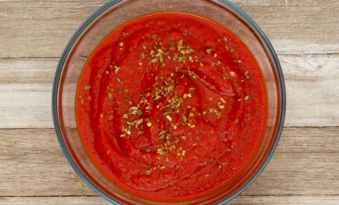 How To Make Pizza Sauce looking down on a bowl of red pizza sauce sitting on a counter