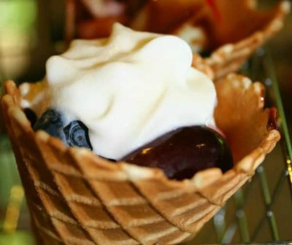 A Fruit Salad Recipe in a waffle ice cream cone with whipped cream on top