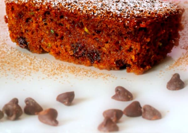 loaf of Chocolate Zucchini Bread sitting on a table with chocolate chips around it