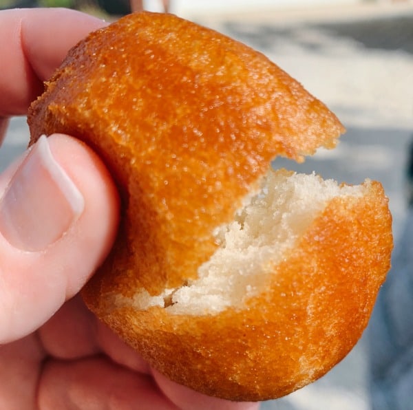 hand holding golden brown fried biscuit broken open to see inside