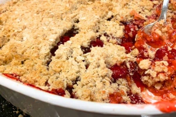 Easy Cherry Crumble Recipe With Perfect Topping Every Time - cherry crumble dessert in a white dish with a spoon in it
