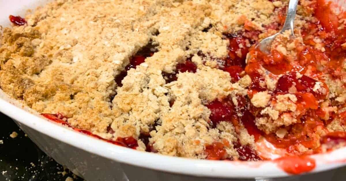 Easy Cherry Crumble Recipe With Perfect Topping Every Time - cherry crumble dessert in a white dish with a spoon in it