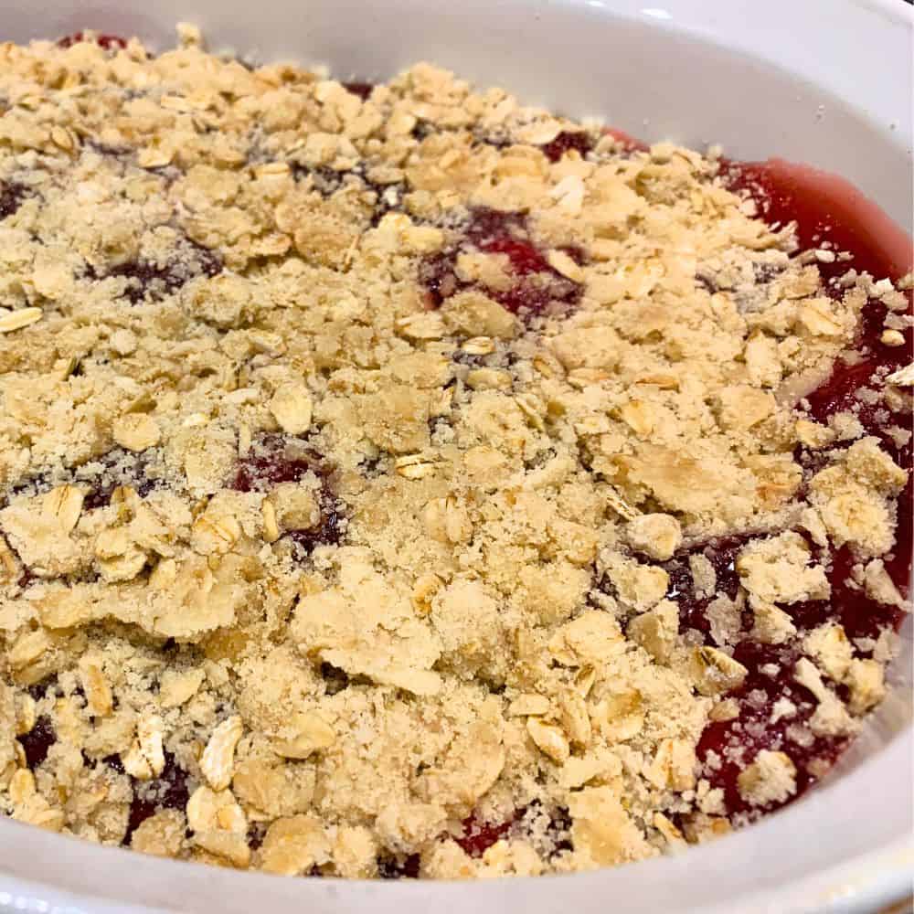 Secret to Crumble Crust and Crumble Topping (Cherry Crumb Pie Recipe) - easy cherry crisp recipe - how to make homemade cherry crumble topping with uncooked cherry crumb topping on top of canned cherries in a white dish