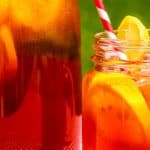Homemade Sun Tea Recipe with full glass tea jar and sun tea in a mason jar with colorful straw sitting on picnic table on a summer day