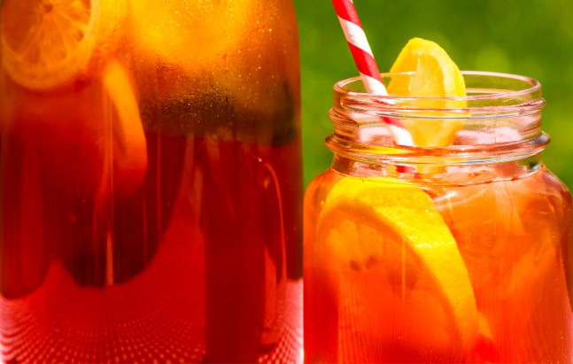 Homemade Sun Tea Recipe with full glass tea jar and sun tea in a mason jar with colorful straw sitting on picnic table on a summer day