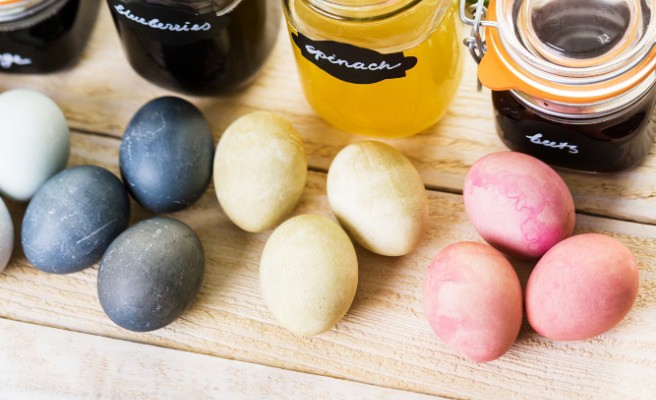 dye eggs naturally blue yellow and pink boiled eggs on a table dyed with food items