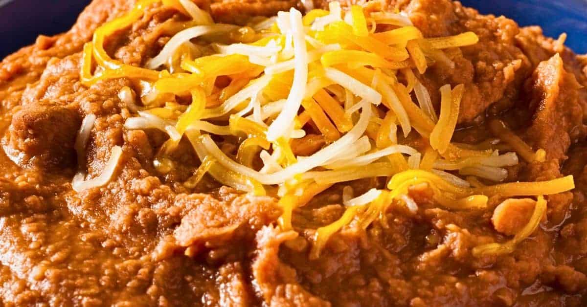 Easy Recipe For Refried Bean Dip (recipes for bean dip with refried beans) close up of refried beans topped with cheese in a bowl