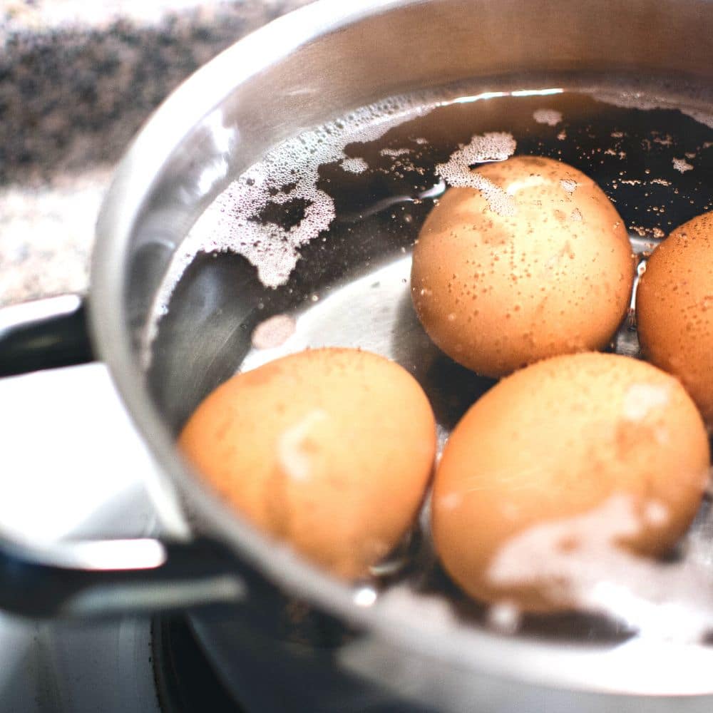 Egg cooking guide and time for boiling eggs (best trick for easy to peel hard boiled eggs) - brown eggs boiling in pot for easy peel eggs