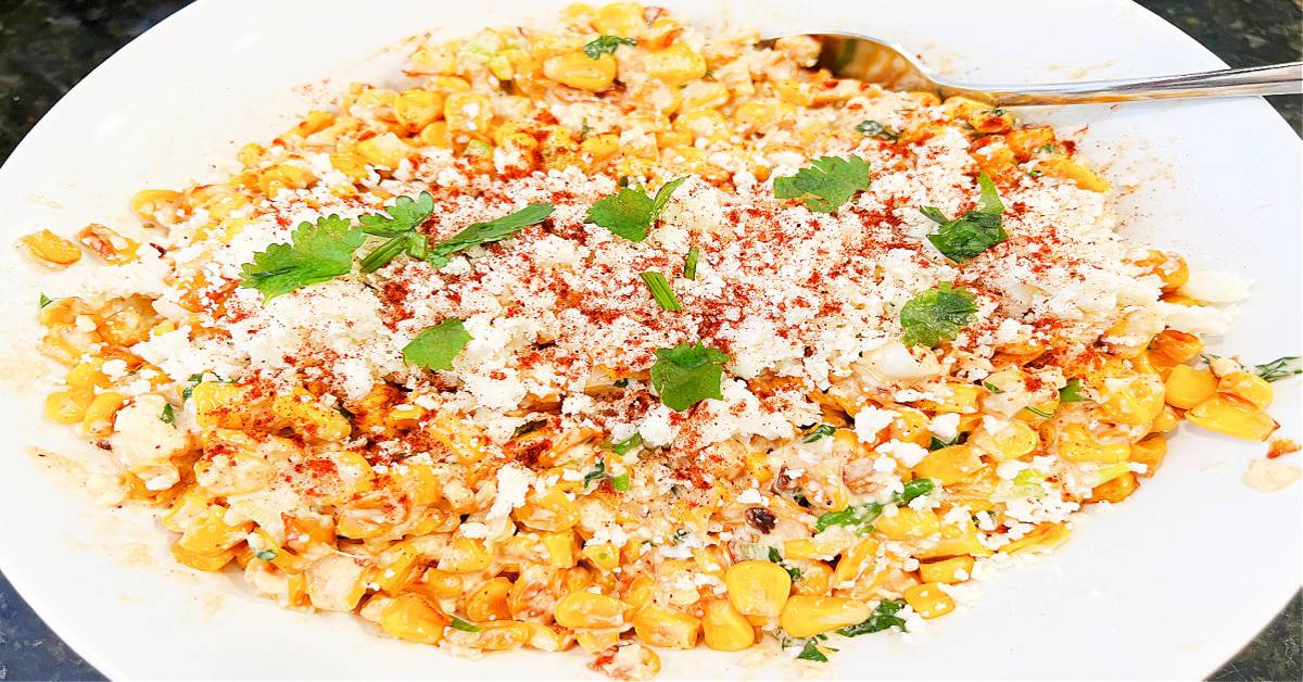 HOW TO MAKE MEXICAN STREET CORN OFF THE COB mexican street corn topped with Cotija white cheese paprika cilantro in a white dish