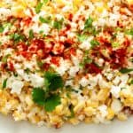 close up of Mexican Street Corn Off the Cob in a dish topped with cheese cilantro and chili powder