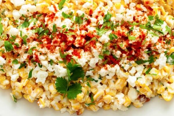 close up of Mexican Street Corn Off the Cob in a dish topped with cheese cilantro and chili powder