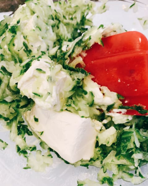 How To Make Cucumber Dip shredded cucumber and cream cheese being stirred with red spatula spoon