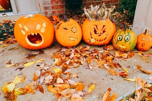 Halloween activities for the family no carve pumpkins on a porch surrounded by autumn leaves