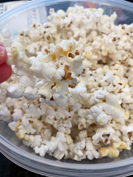 RECIPE FOR KETTLE CORN with fingers holding popped kettle korn