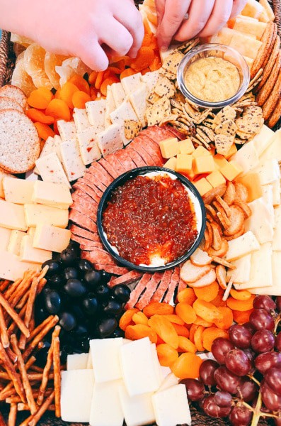 Grazing Charcuterie Board for Parties - HANDS MAKING A GRAZE BOARD