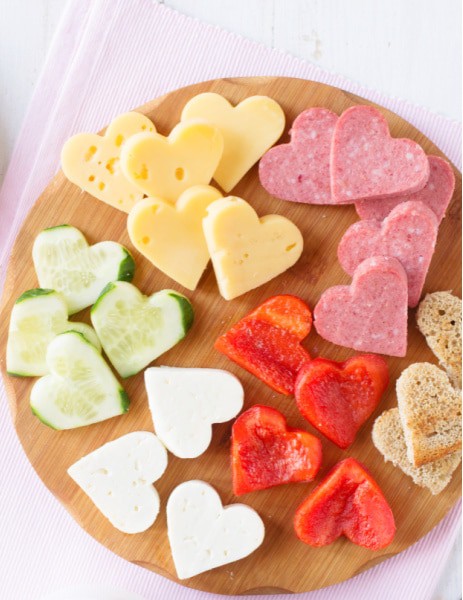 Valentine's Day Charcuterie Board with meats, cheese, cucumbers, red peppers, and bread cut into mini heart shapes