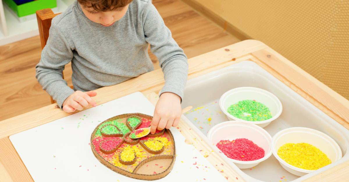 Fun Easter Activities For The Family [Easter Ideas for Kids] young boy sorting colored rice into a cardboard Easter egg