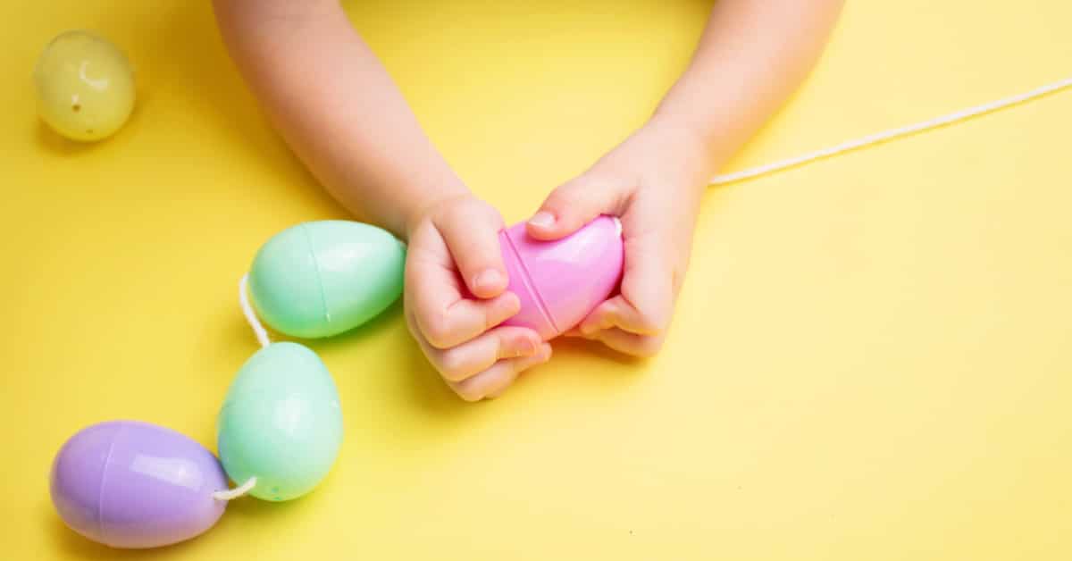 Games To Play With Easter Eggs overhead view of a child playing games with plastic Easter eggs on a yellow table