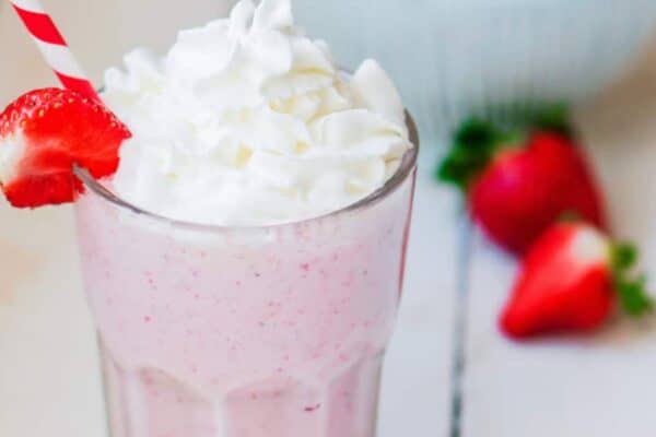 milkshake strawberry recipe on a white table with fresh strawberries in the background