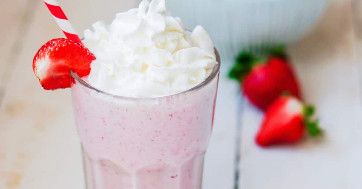 milkshake strawberry recipe on a white table with fresh strawberries in the background