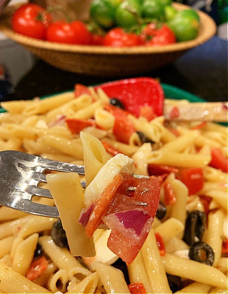 Recipes For Cold Italian Pasta Salad (pasta salad with pepperoni and Italian dressing) on a fork in front of pasta bowl