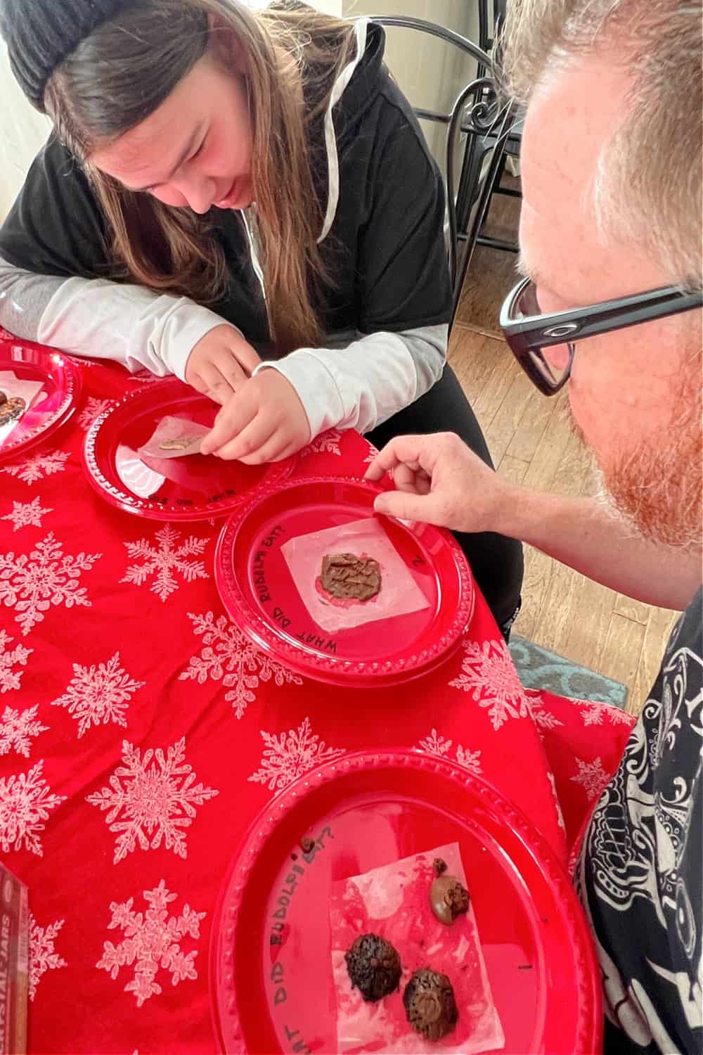 How Do You Play The Reindeer Poop Christmas Game with people sitting around a red table playing the holiday game