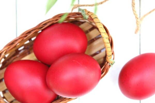 Red colored eggs in a basket on a white table