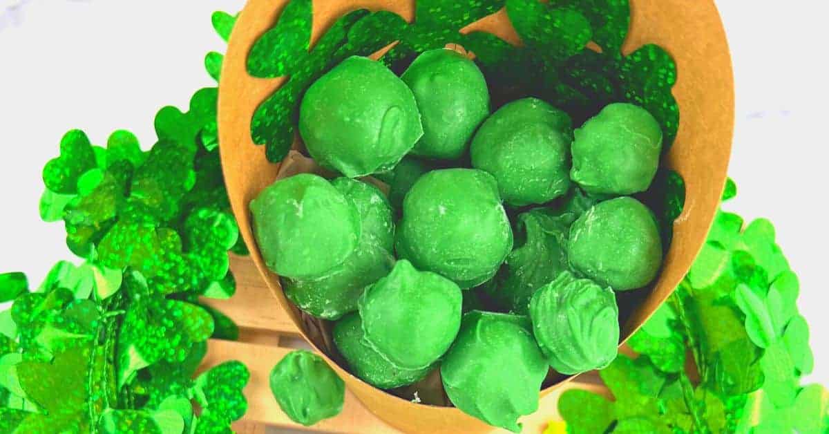 St Patricks Day Leprechaun Poop Treats For Kids (leprechaun candy) in a brown paper cup surrounded by foil shamrocks