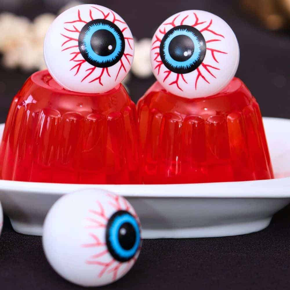 Halloween Eyeball Jello 2 small cups of red store bought jello on plates with big Halloween eyes on top